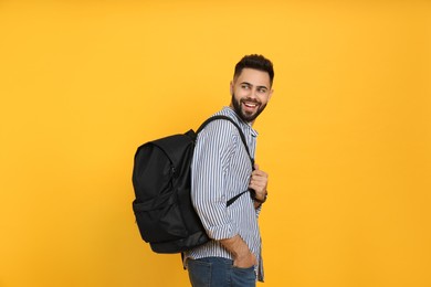 Photo of Young man with stylish backpack on yellow background