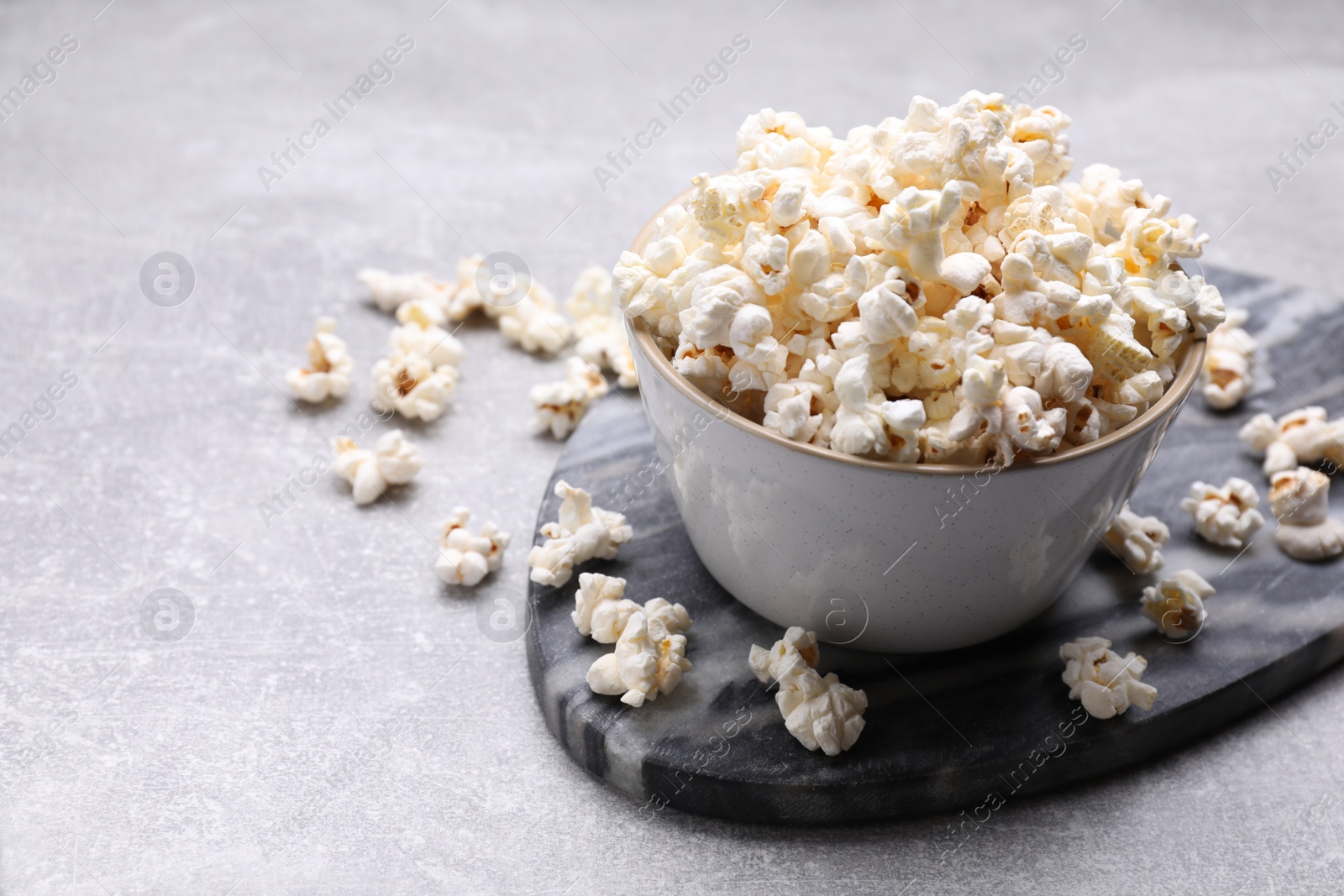 Photo of Bowl of tasty popcorn on grey table, space for text