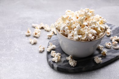 Photo of Bowl of tasty popcorn on grey table, space for text