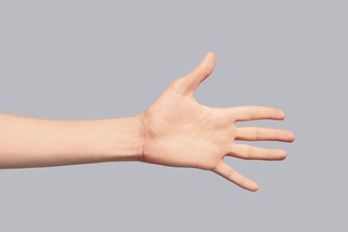 Photo of Young woman showing hand on grey background, closeup