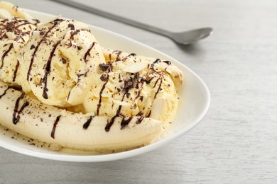 Delicious banana split ice cream with toppings on white wooden table, closeup
