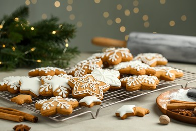 Tasty Christmas cookies with icing and spices on table against blurred lights