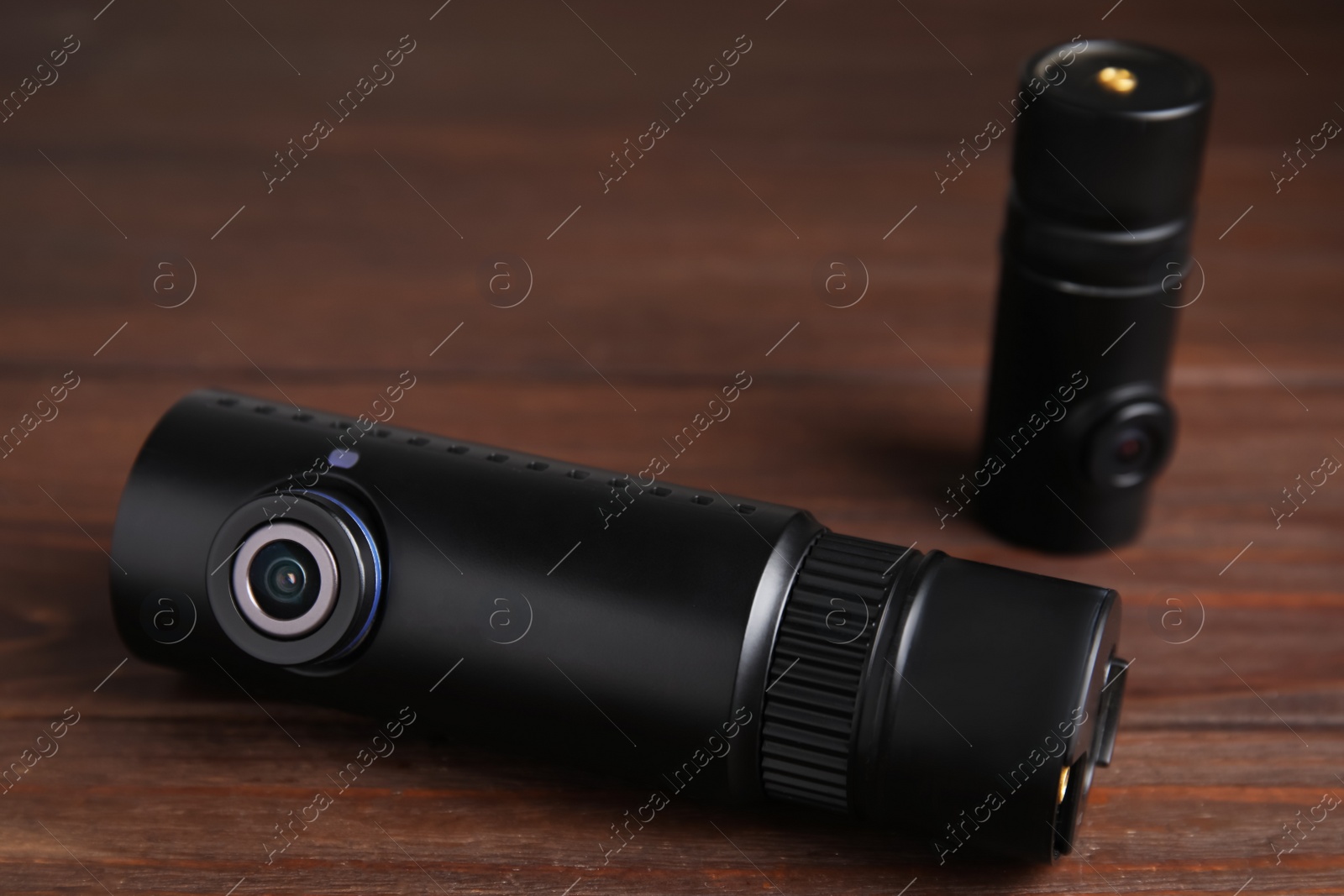 Photo of Black modern car cameras on wooden table, closeup