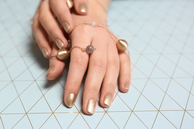 Photo of Woman with golden manicure on color background, closeup. Nail polish trends