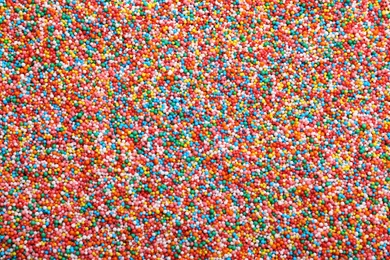 Photo of Bright colorful sprinkles as background, top view. Confectionery decor