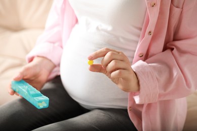 Photo of Pregnant woman holding pill on blurred background closeup