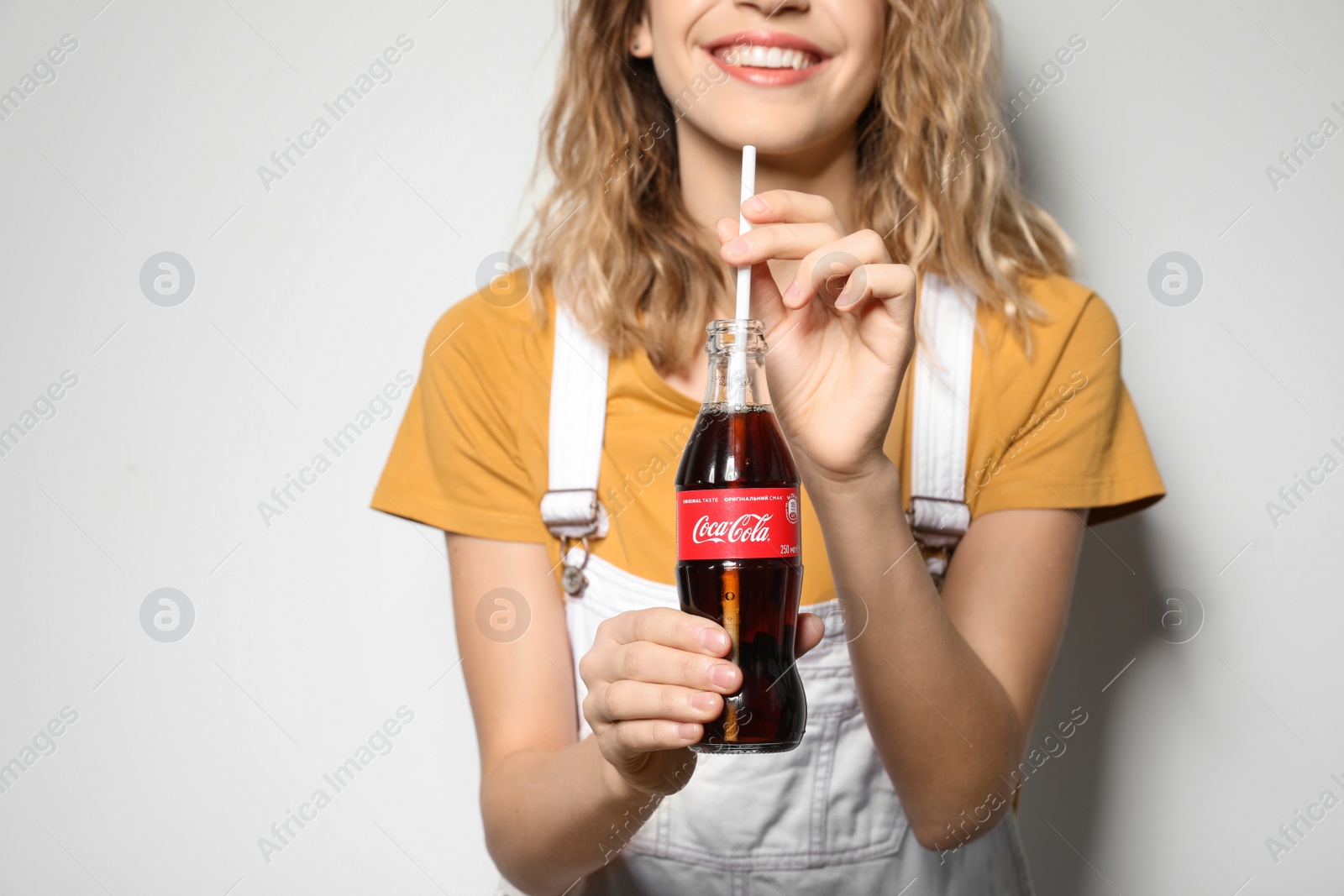 Photo of MYKOLAIV, UKRAINE - NOVEMBER 28, 2018: Young woman with bottle of Coca-Cola on white background, closeup