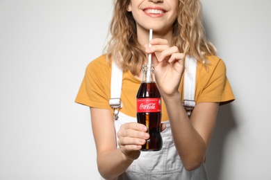 Photo of MYKOLAIV, UKRAINE - NOVEMBER 28, 2018: Young woman with bottle of Coca-Cola on white background, closeup