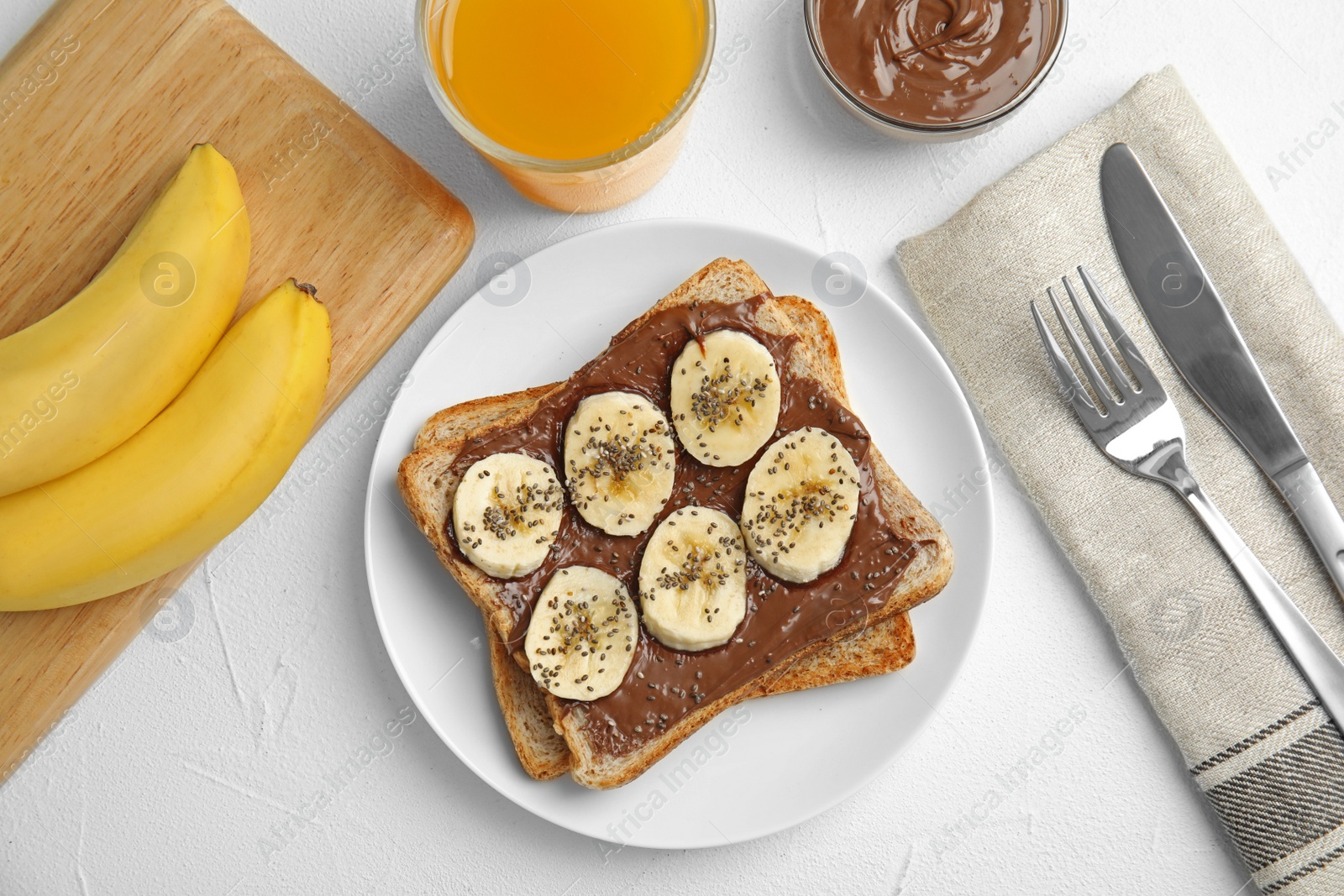 Photo of Slice of bread with chocolate paste and banana on white table, flat lay