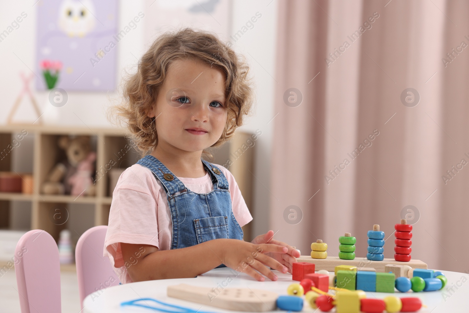 Photo of Motor skills development. Little girl playing with toys at table indoors