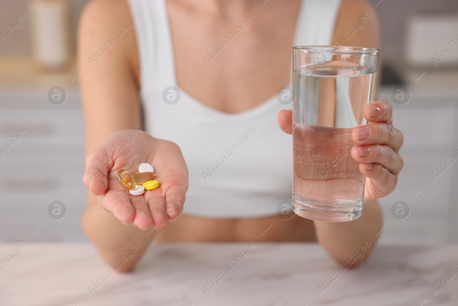 Photo of Woman with glass of water and pills at table indoors, closeup. Weight loss