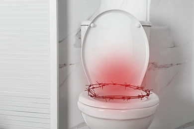 Image of Hemorrhoid concept. Toilet bowl with barbed wire in rest room