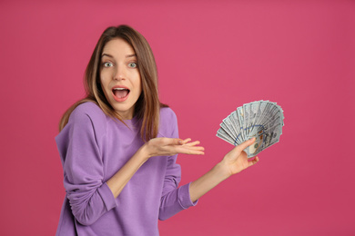 Photo of Surprised young woman with cash money on pink background