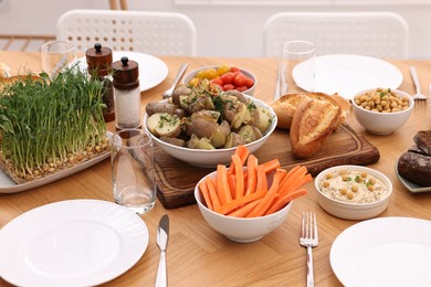 Photo of Healthy vegetarian food, glasses, cutlery and plates on wooden table indoors