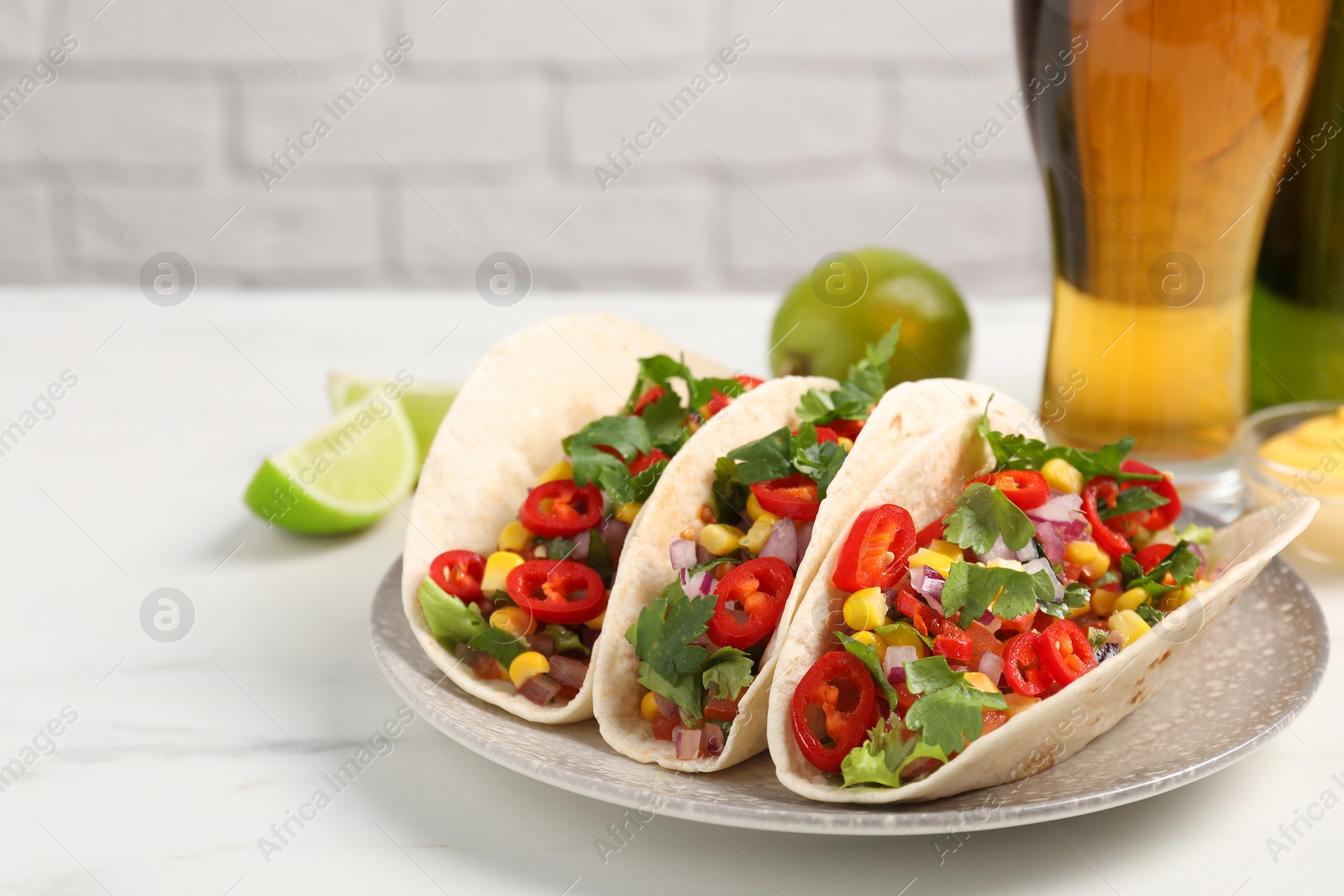 Photo of Tasty tacos with vegetables on white marble table, space for text