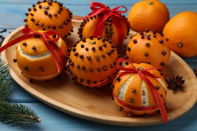 Pomander balls made of tangerines with cloves and fir branch on light blue wooden table