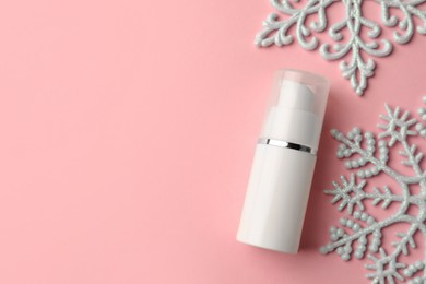 Winter skin care. Hand cream near snowflakes on pink background, flat lay. Space for text