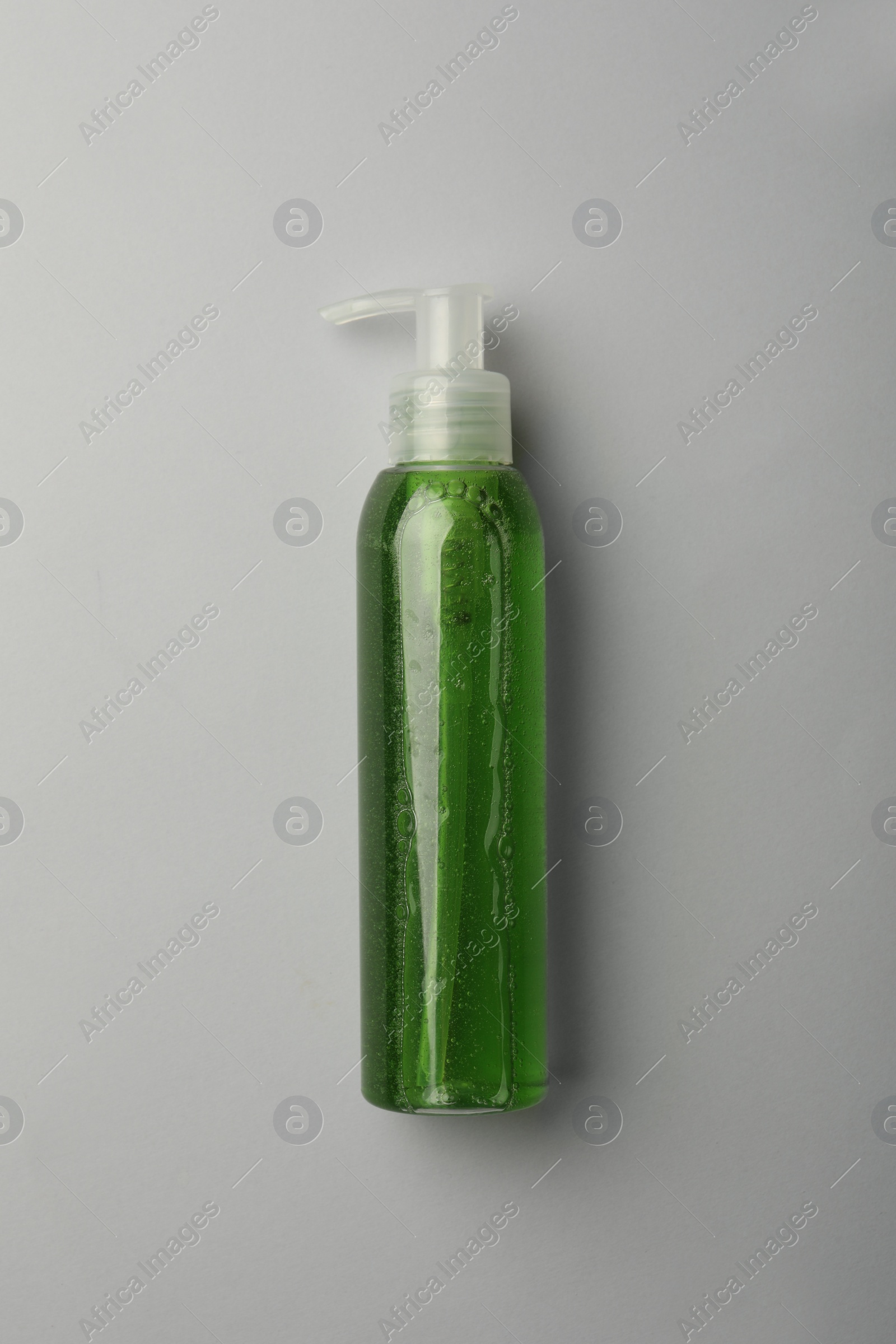 Photo of Bottle of green cosmetic gel on light background, top view
