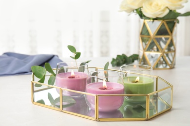 Tray with burning candles and eucalyptus on light table