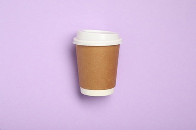 Photo of Takeaway paper coffee cup on violet background, top view