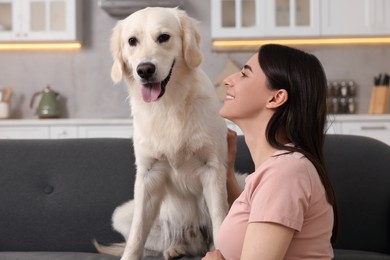 Photo of Happy woman with cute Labrador Retriever dog on sofa at home. Adorable pet