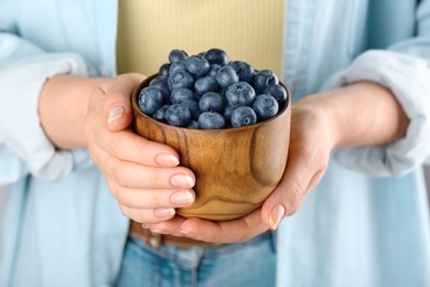 Photo of Woman holding tasty fresh blueberries, closeup view