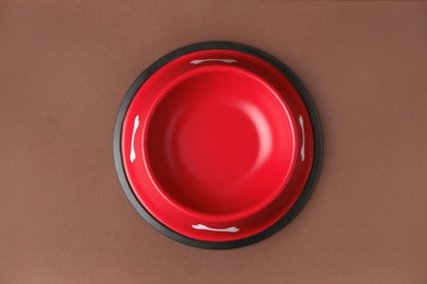 Photo of Empty red feeding bowl on brown background, top view