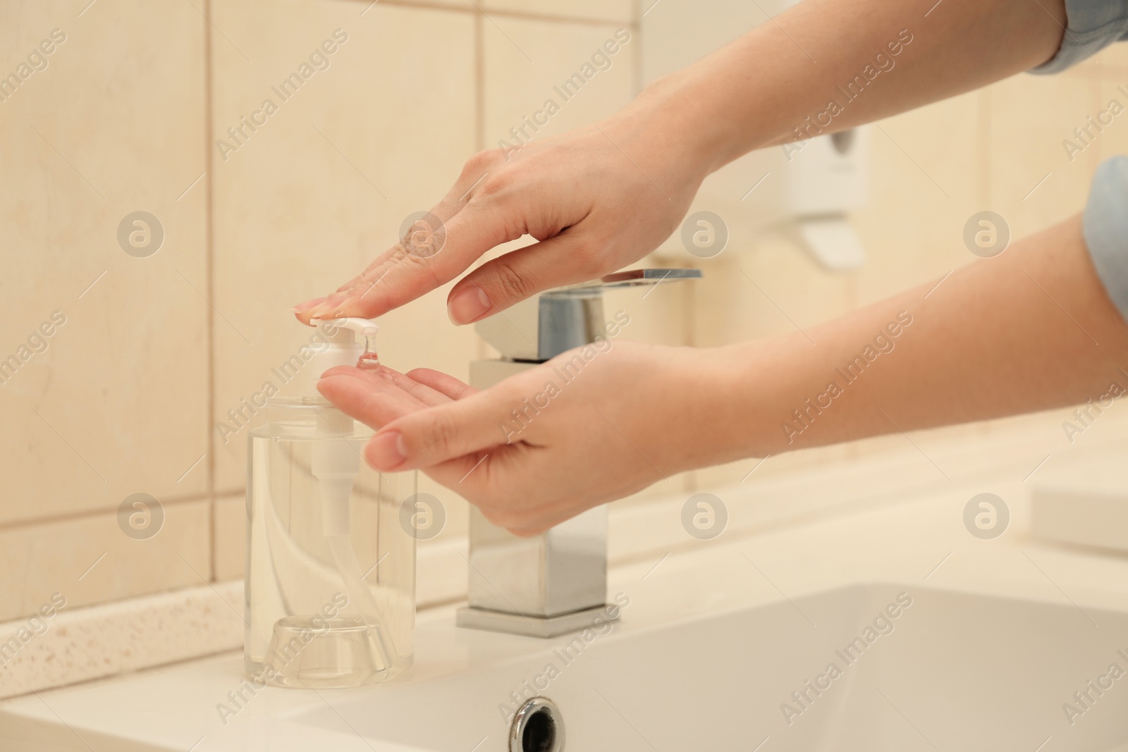 Photo of Woman applying antiseptic soap onto hand in bathroom, closeup. Virus prevention