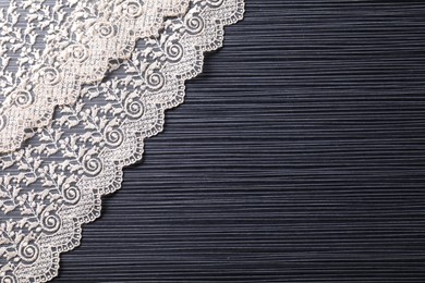 White lace on black table, top view. Space for text