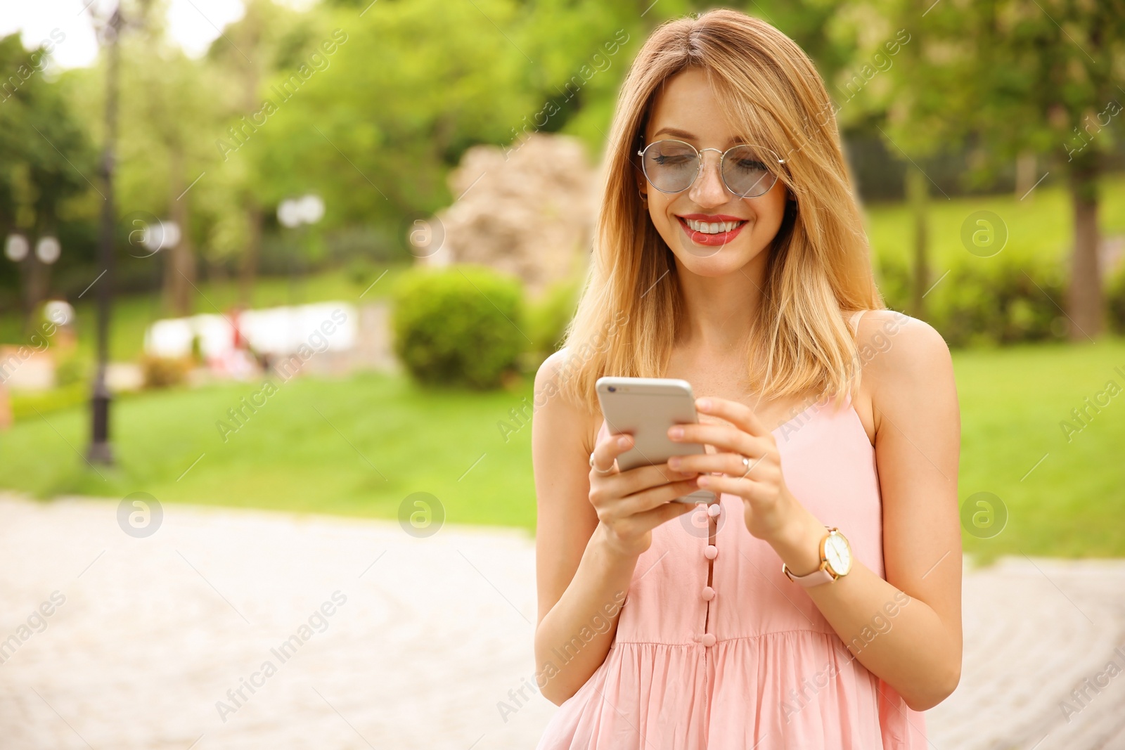 Photo of Young woman in stylish outfit with smartphone outdoors
