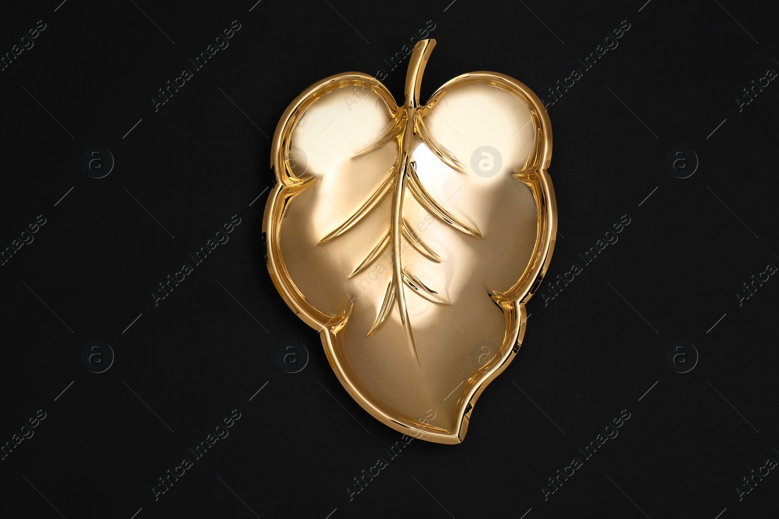 Photo of Gold leaf shaped bowl on black background, top view