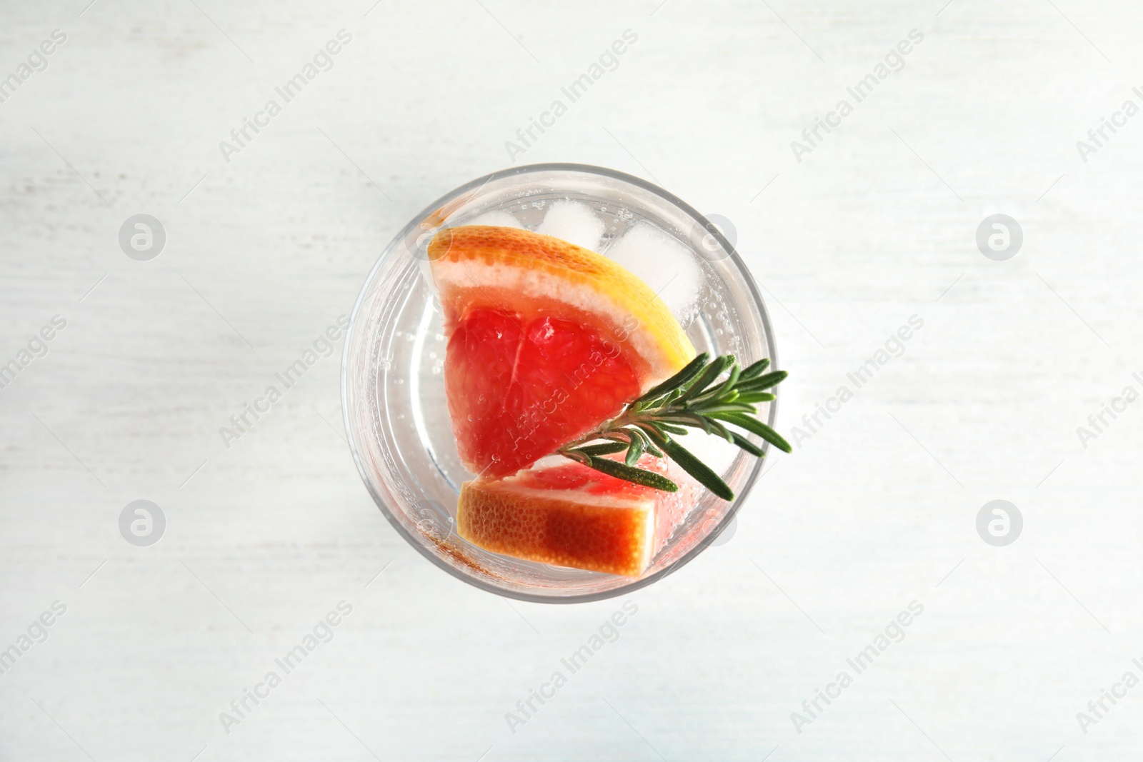 Photo of Glass of infused water with grapefruit slices on white table, top view