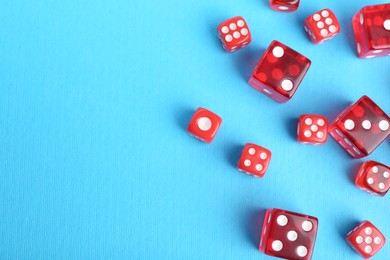 Photo of Many red game dices on light blue background, flat lay. Space for text