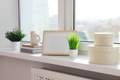 Photo of Potted artificial plants, books and decor on windowsill indoors