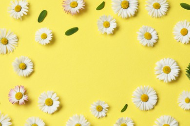 Photo of Frame of daisy flowers and leaves on yellow background, flat lay. Space for text