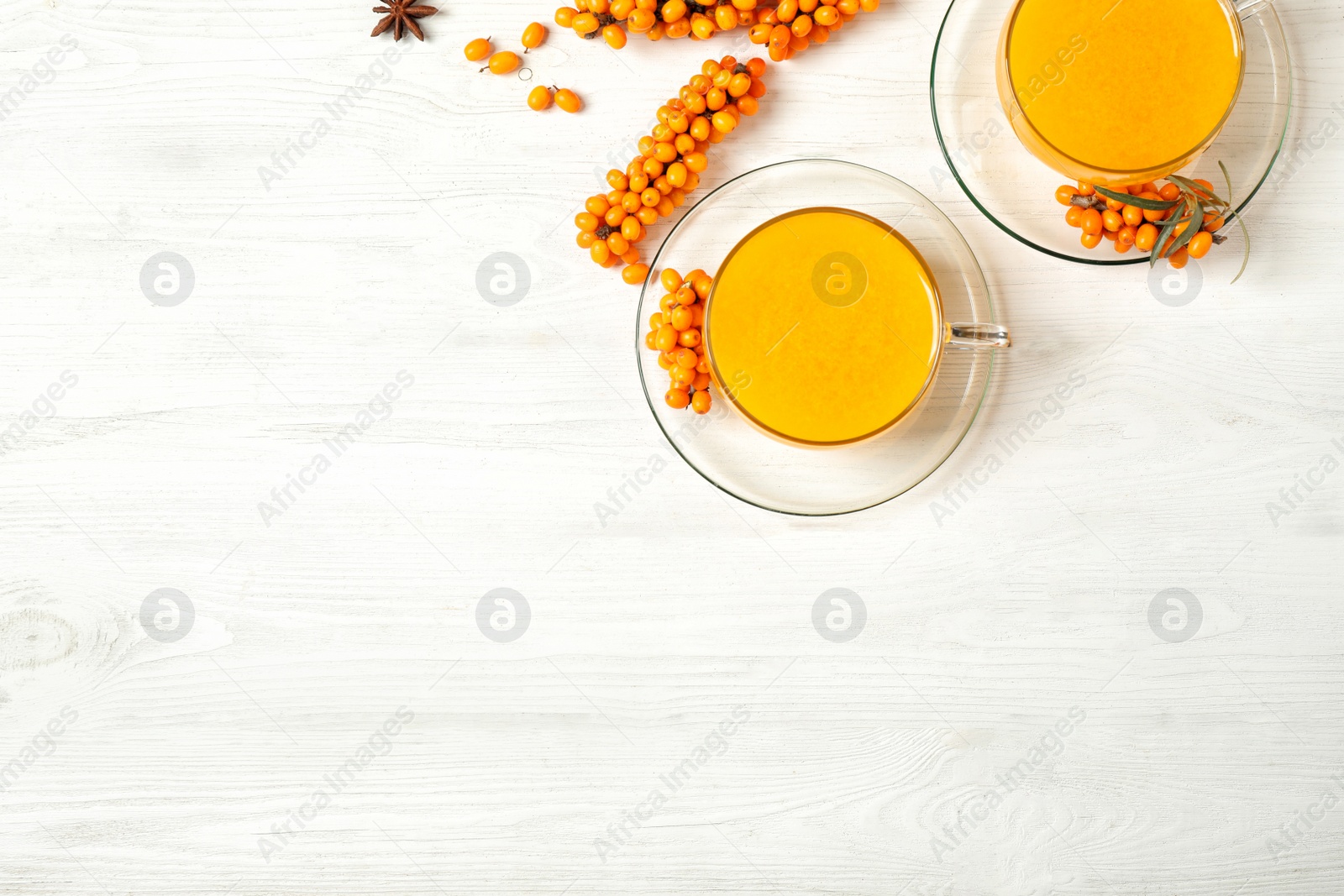 Photo of Delicious sea buckthorn tea and fresh berries on white wooden table, flat lay. Space for text