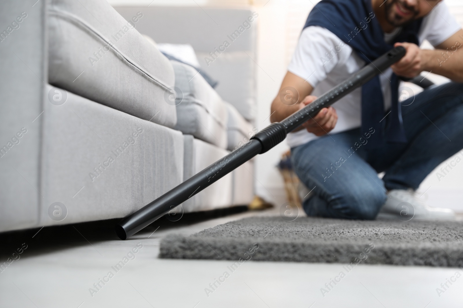 Photo of Young man using vacuum cleaner at home, closeup