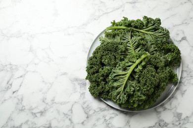 Photo of Fresh kale leaves on white marble table, top view. Space for text