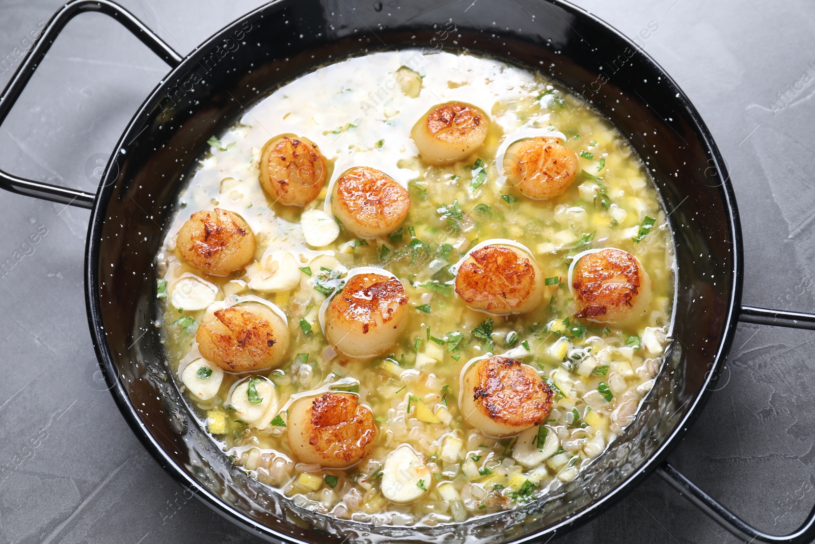 Photo of Fried scallops with sauce in dish on grey table, above view