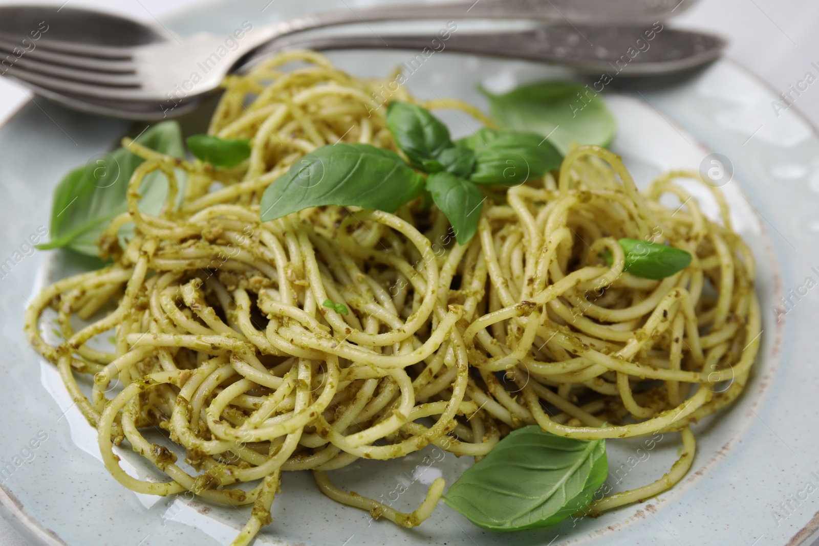 Photo of Delicious pasta with pesto sauce and basil on plate, closeup