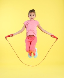 Photo of Full length portrait of girl jumping rope on color background