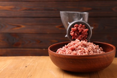 Photo of Manual meat grinder with beef mince on wooden table, space for text