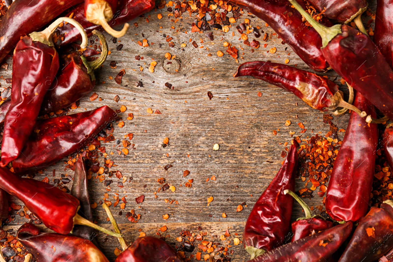 Photo of Dry chili peppers and powder on wooden background