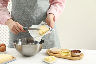 Photo of Woman adding fresh butter into bowl at white wooden table, closeup