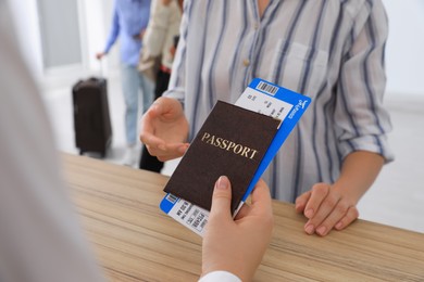 Photo of Agent giving passport with ticket to client at check-in desk in airport, closeup