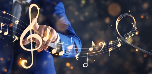 Image of Musician pointing at staff with music notes and symbols on color background, closeup. Banner design