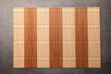 Photo of Bamboo mat on grey table, top view. Space for text