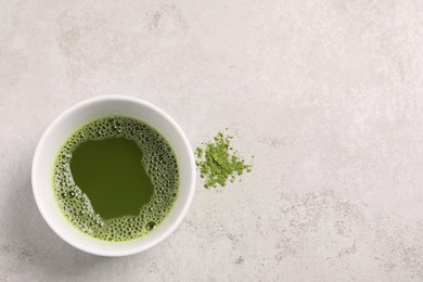 Photo of Cup of matcha tea on light gray textured table, top view. Space for text