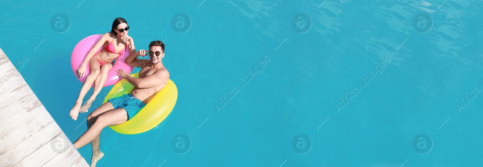 Image of Happy young couple at swimming pool, space for text. Banner design