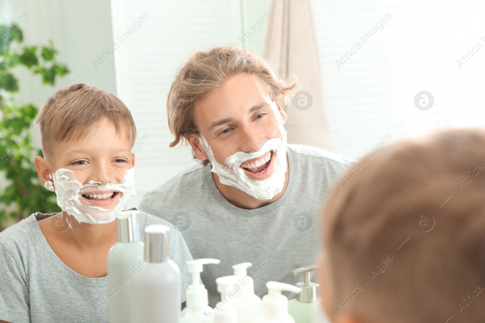 Photo of Father and son with shaving foam on faces in bathroom